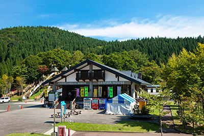 晴れた日の山に囲まれたキャンプ場の受付棟の写真