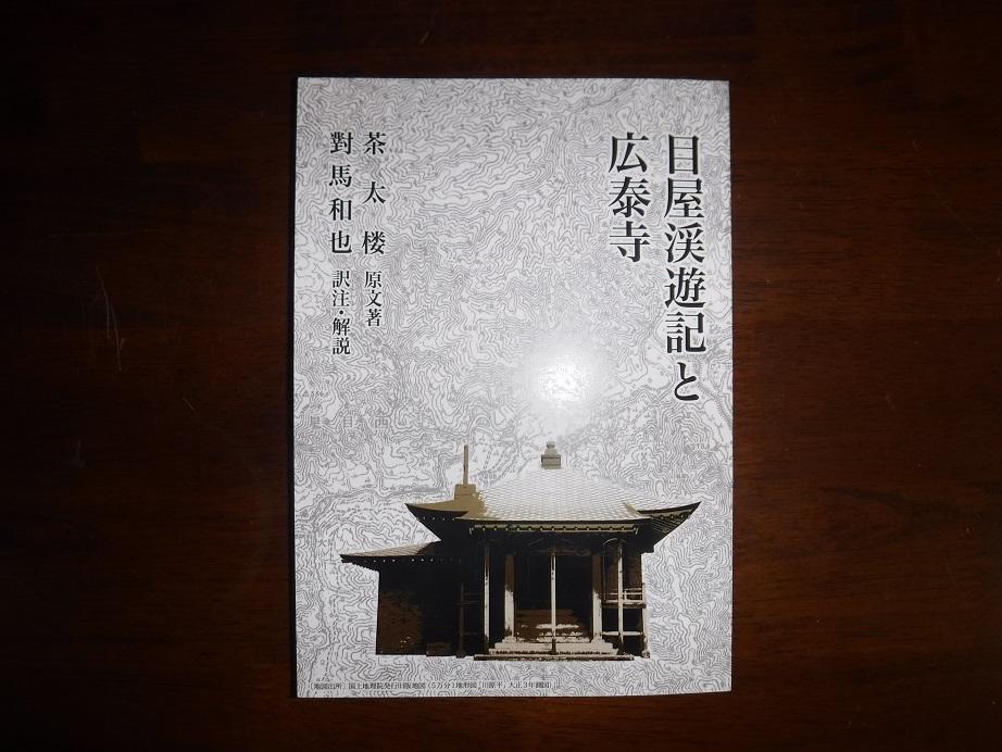 「目屋渓遊記と広泰寺」と書かれた本の表紙を、机の上に置いて真上から見た写真
